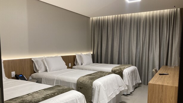 Une chambre d’hôtel avec deux lits, un bureau en bois, un téléphone et un rideau.