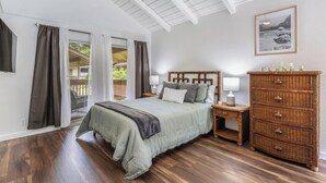 Une chambre à coucher avec un lit, des tables de chevet, une commode et une fenêtre avec des rideaux.