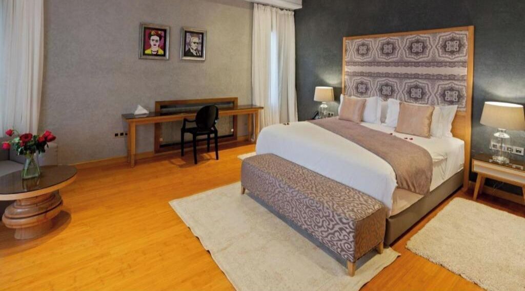 Een hotelkamer met een groot bed, een bureau, een stoel en een tafeltje met een bloevas.