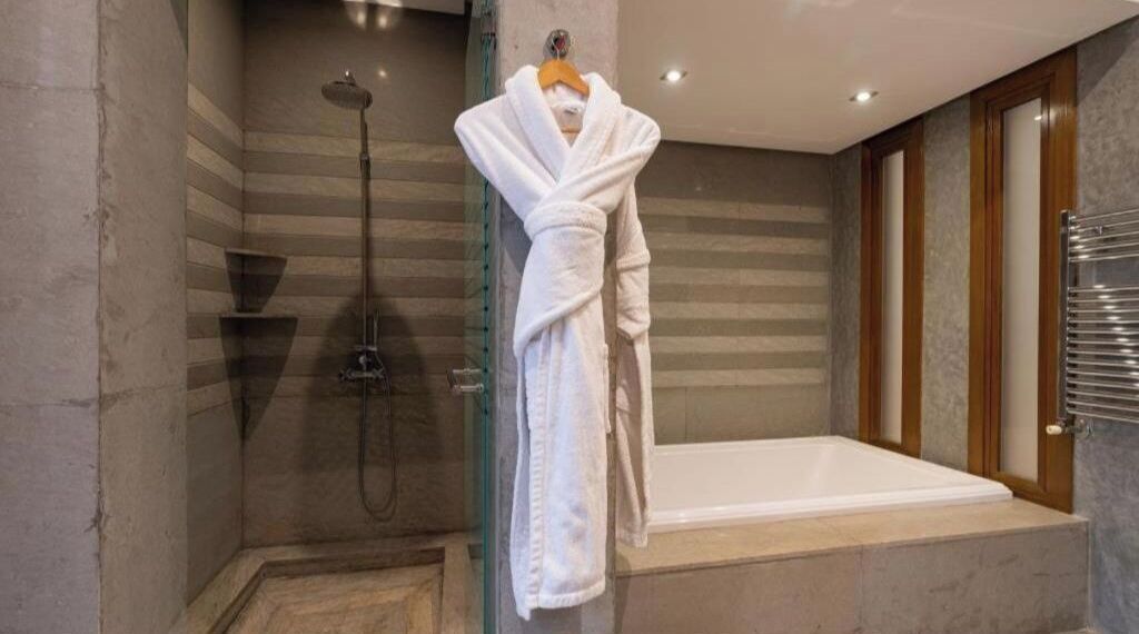 A bathroom with a glass-enclosed shower, a bathtub, and a hanging robe rack.