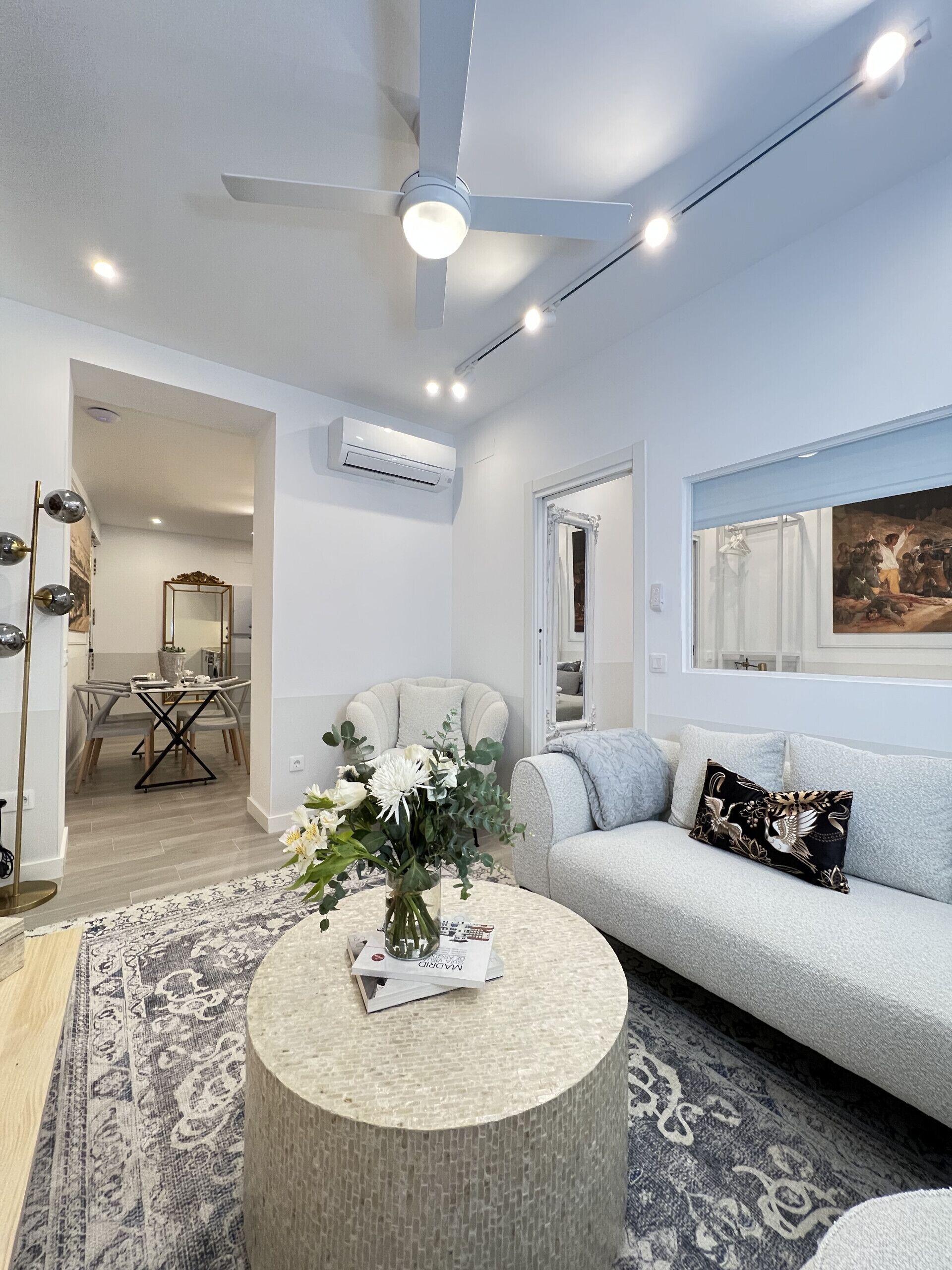 A modern living room with a round coffee table, a sofa, and a dining area in the background.
