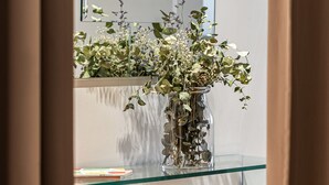 Un vaso di vetro con fiori secchi su una mensola di vetro.