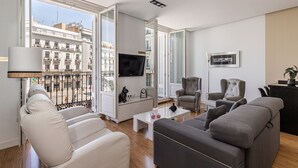 Un soggiorno moderno con un divano, poltrone, un tavolino da caffè e una televisione.