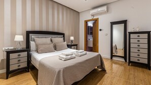 Una camera da letto ordinata con un letto, comodini, una cassettiera e un condizionatore d'aria.