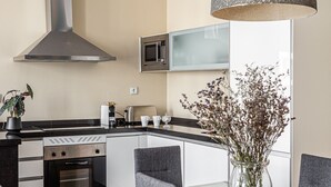 Una cucina moderna con isola centrale, elettrodomestici in acciaio inossidabile e zona pranzo con tavolo e sedie in vetro.
