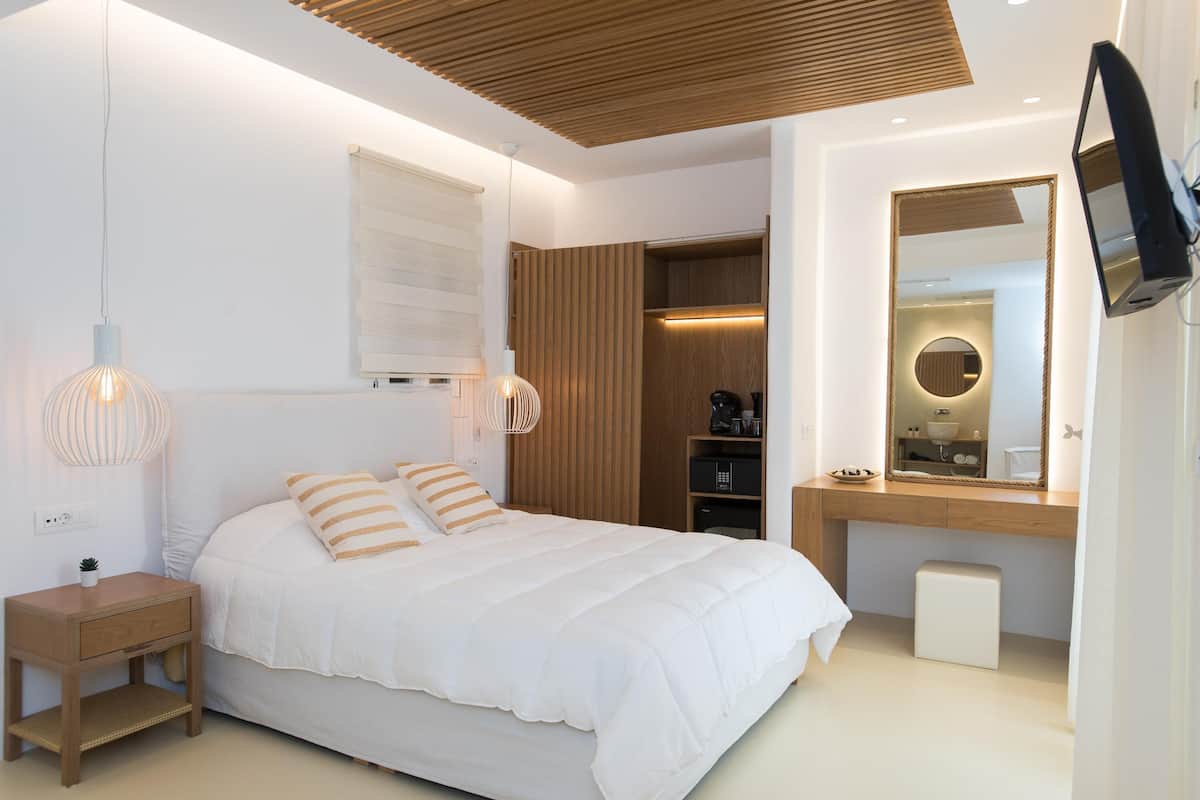 Un dormitorio moderno con cama, mesita de noche y televisor montado en la pared.