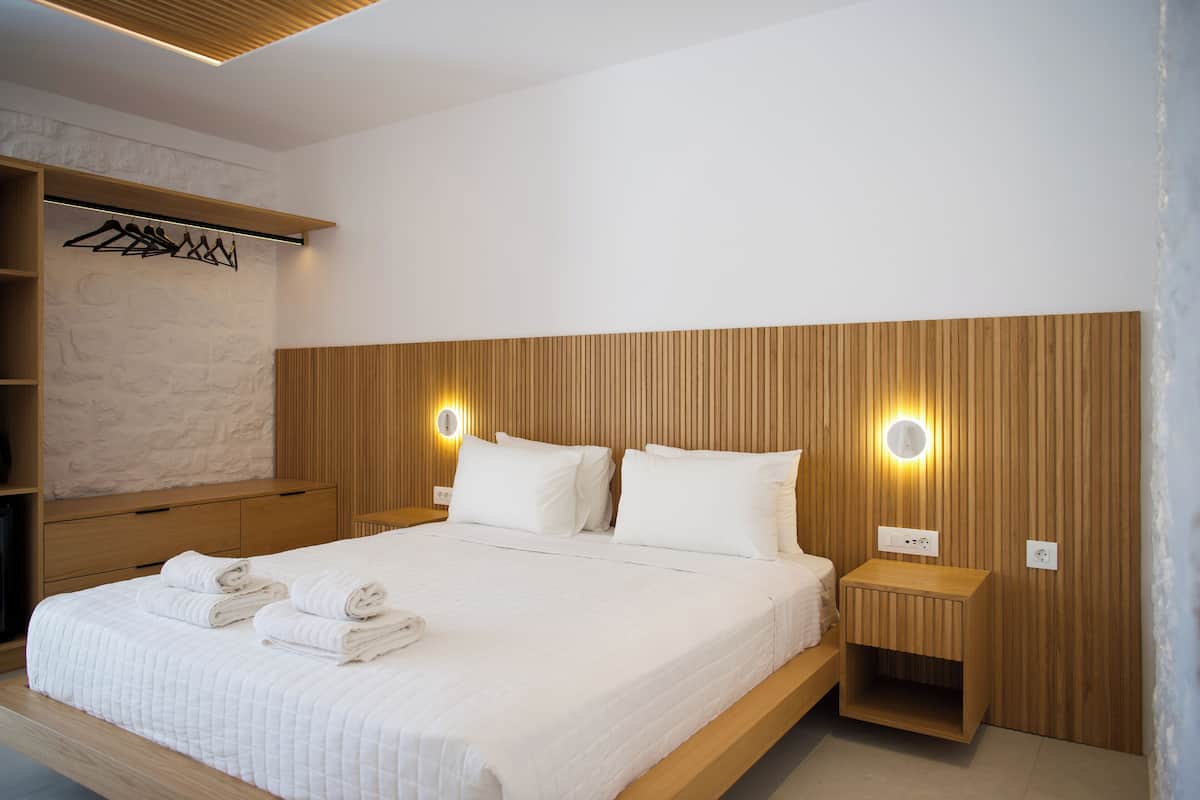 Un dormitorio moderno con cabecera de madera, armario empotrado y mesitas de noche con iluminación integrada.