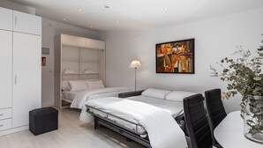 Un dormitorio moderno con dos camas, un armario, un cuadro y una planta.