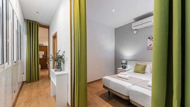Una camera d'albergo moderna con un letto, un comodino e un condizionatore d'aria.