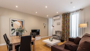 Una sala de estar moderna con comedor, un sofá, un televisor y una mesa de centro.