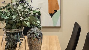 Una mesa de comedor con dos jarrones de flores y una obra enmarcadas en la pared.