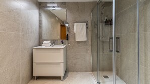 A modern bathroom with a glass shower enclosure, a white vanity, and a large mirror. - Waou Apartamentos en Sol Confort 6 (Madrid)