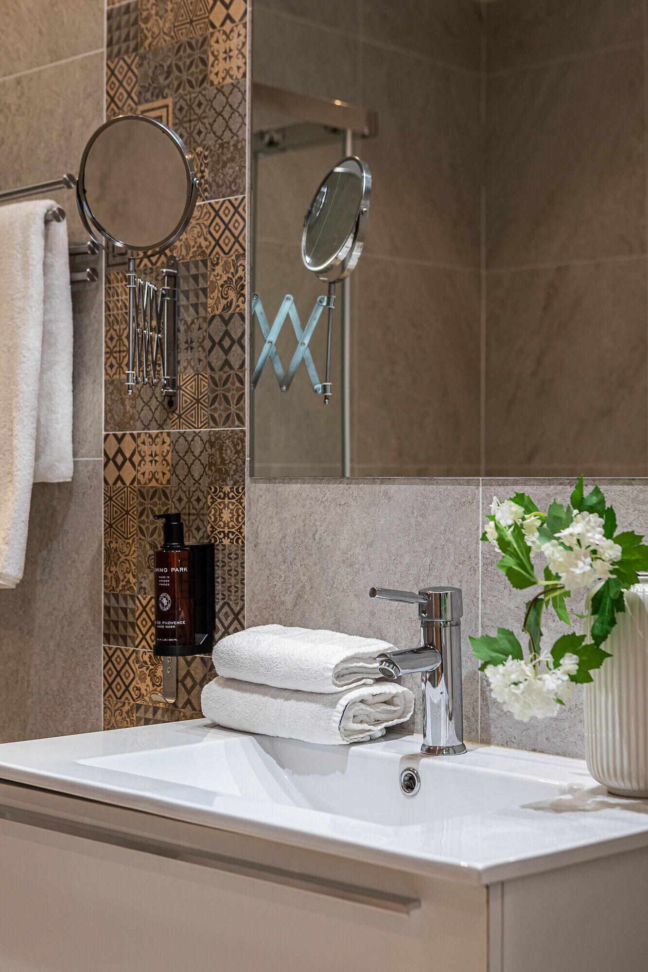 A modern bathroom with a white sink, a mirror, and a towel rack.