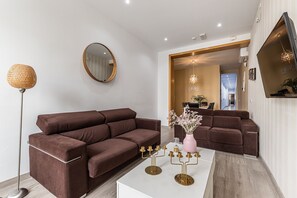 Ein modernes Wohnzimmer mit einem braunen Ecksofa, einem weißen Couchtisch und einer Stehlampe.