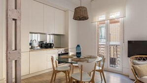 A modern kitchen with white cabinets, a glass dining table, and a hanging light fixture. - Waou La Latina IV - Alquiler Corta Duración (Madrid)