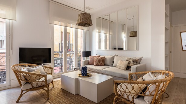 A modern living room with a sofa, two wicker chairs, a coffee table, and a TV. - Waou La Latina IV - Alquiler Corta Duración (Madrid)