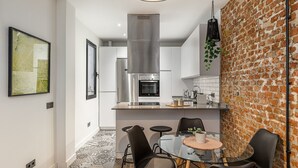 A modern kitchen with stainless steel appliances, a glass dining table, and black chairs.