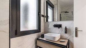 A modern bathroom with a large window, a white sink, and a mirror above it.