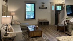 Ein geräumiges Wohnzimmer mit einer Couch, einem Couchtisch und einem an der Wand montierten Fernseher.