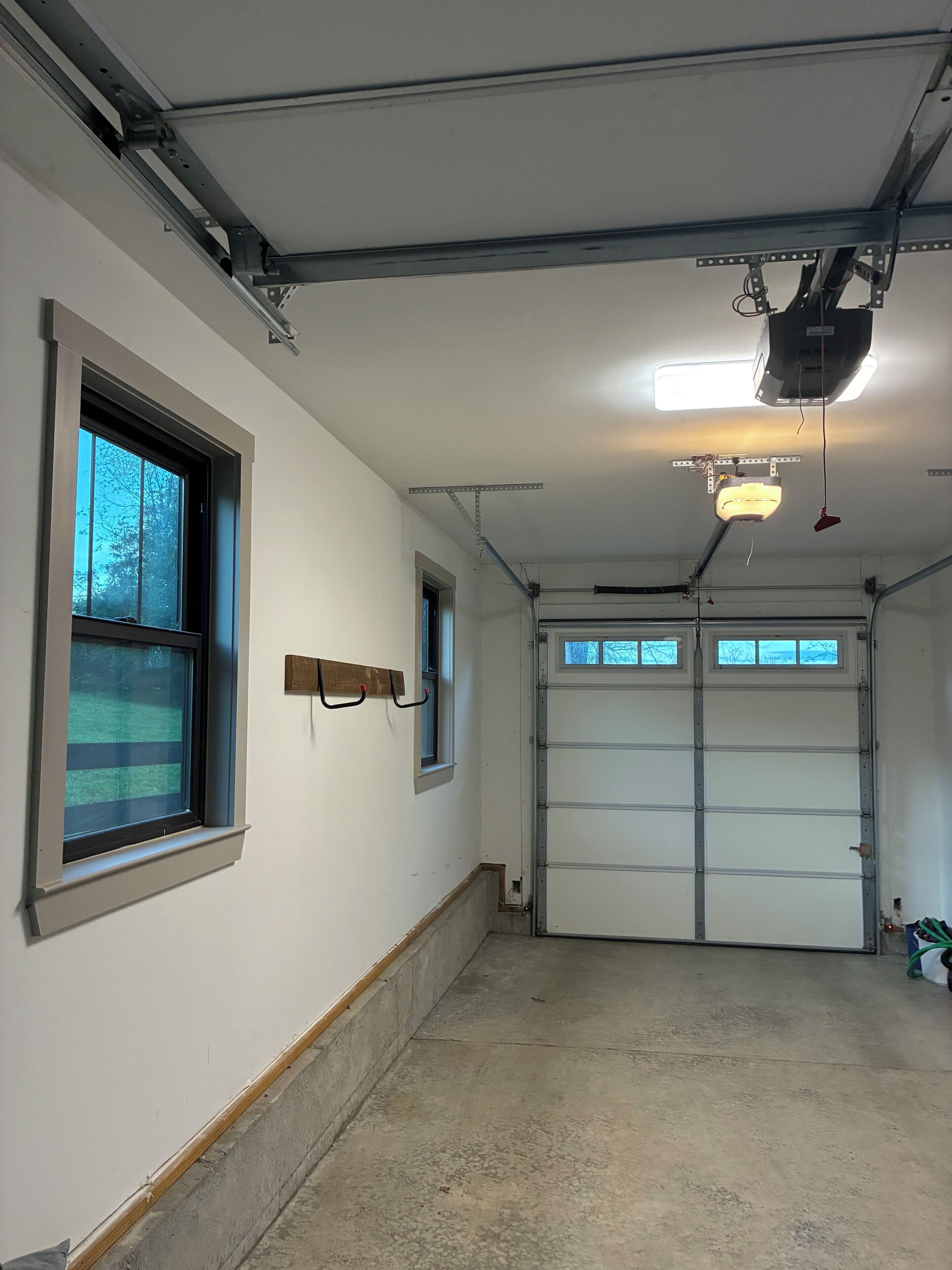 Un garage avec deux fenêtres, un luminaire fixé au plafond et une porte de garage.