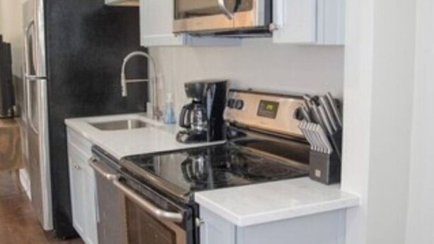 A modern kitchen with stainless steel appliances, a built-in oven, and a coffee maker. - Iconic Home across from Ponce City Market (Atlanta)