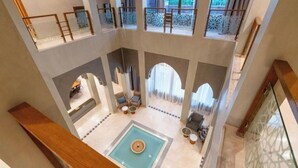 A multi-level atrium with a central pool, multiple seating areas, and a view of the outdoors. - Mimouna Riads- Luxury villa 17 bedrooms (Marrakech)