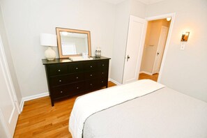 Une chambre à coucher avec un lit, une commode, un miroir et une table de chevet.