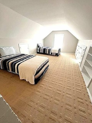 Un dormitorio con dos camas, un armario y una puerta.