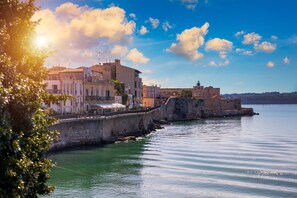 Une ville côtière dotée de bâtiments historiques le long du front de mer, d’un mur de pierre et d’un ciel dégagé.