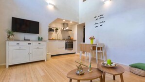 A modern kitchen with white cabinets, a dining area with a wooden table and chairs, and a wall with motivational text.