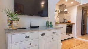 A modern kitchen with a flat-screen TV, a built-in oven, and a stainless steel refrigerator.