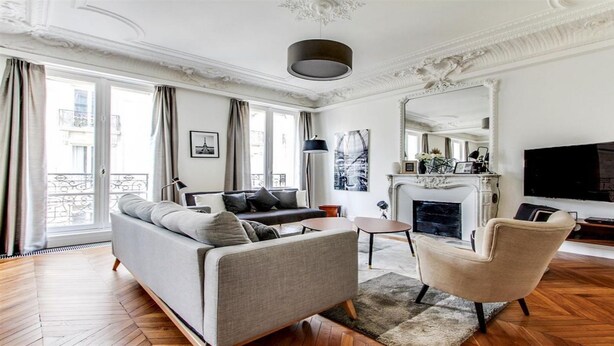 A modern living room with a sofa, armchair, fireplace, and a large TV. - TOP OF THE RANGE - CHAMPS ELYSEE LUXE 110M2 (Paris)