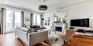 Una sala de estar moderna con un sofá, un sillón, una chimenea y un televisor grande.