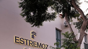The exterior of the Estremoz Hotel with a signboard, a tree, and a bench. - Estremoz Hotel (Estremoz)