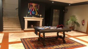 A lobby with a fireplace, a table with magazines, a staircase, and a large painting on the wall. - Estremoz Hotel (Estremoz)