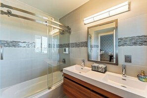 A modern bathroom with a glass-enclosed shower, a white sink with a wooden vanity, and a large mirror.