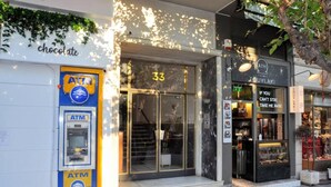 A storefront with an ATM, a chocolate shop, and a restaurant named 'SOUVLAKI'. - Acropolis museum grand apartment (Athina)