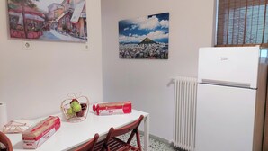 A small dining area with a table, chairs, a basket of fruit, and a refrigerator. - Stunning Acropolis view apartment (Athina)