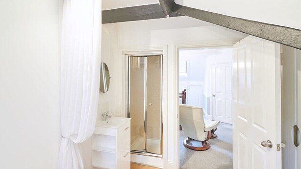 A bedroom with a bed, a bathroom with a shower, and a door leading to another room. - Host & Stay | Park Place Apartment (Whitby)
