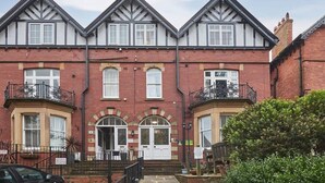 A row of three-story houses with a symmetrical facade, featuring a central entrance with a white door and a small porch. - Host & Stay | Park Place Apartment (Whitby)