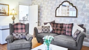 A living room with two grey armchairs, a grey sofa, and a white coffee table with a vase of flowers. - Host & Stay | Park Place Apartment (Whitby)