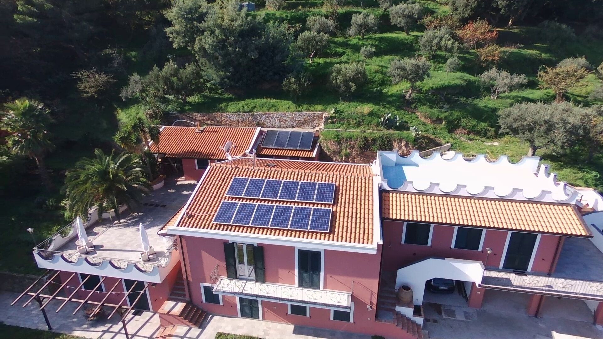 Une maison à deux étages, dotée de panneaux solaires sur le toit et entourée de verdure.