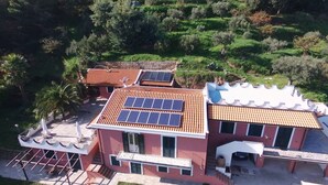Une maison à deux étages, dotée de panneaux solaires sur le toit et entourée de verdure.