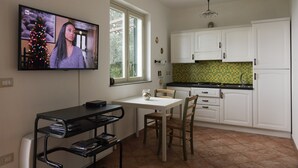 Une cuisine avec des meubles blancs, un pare-feu en carrelage et un coin repas comprenant une table et des chaises.