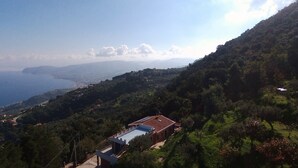 Un village côtier avec des maisons à étages, une vue dégagée sur la mer et un paysage montagneux en arrière-plan.