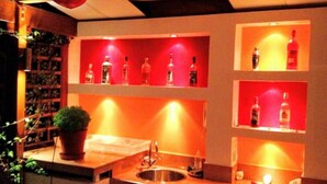 Angolo bar con scaffali che espongono bottiglie, un lavello e una pianta in vaso.
