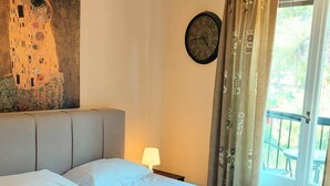 Camera d'albergo con un letto grande, un quadro appeso al muro, una sveglia e vista sull'esterno attraverso una finestra.