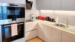 A modern kitchen with a built-in oven, a coffee maker, a toaster, and a sink. - Elegant apartment in Acropolis (Athina)
