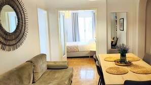 A room with a wooden dining table, a sofa, a mirror, and a framed picture on the wall. - Magnificent apartment in Plaka (Athina)