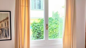 A room with a framed picture of a building, a window with curtains, and a door with a handle. - Magnificent apartment in Plaka (Athina)